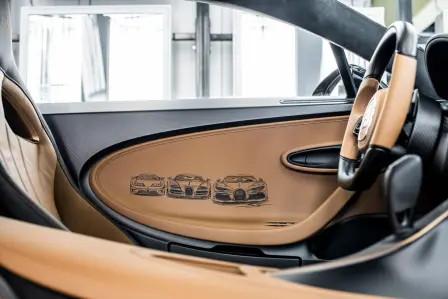 Trois Bugatti modernes, la EB110, la Veyron et la Chiron, sont peintes directement sur le cuir qui habille le panneau de porte côté conducteur.  