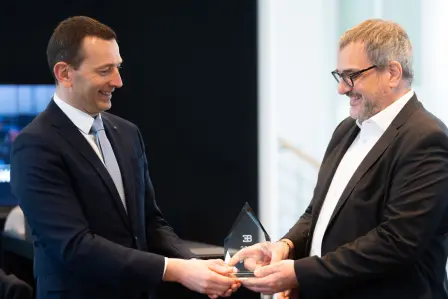 Alexis Ploix, Director of Aftersales and Customer Service at Bugatti, hands the glass trophy to Eligio Camiña, Bugatti Zurich Brand Manager and Aftersales Manager.